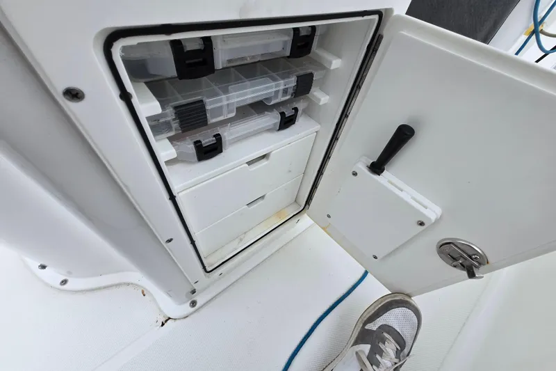 Slide: The Image of 2020 Sea Hunt Gamefish 25 tackle storage compartment with open door and visible trays. - 23