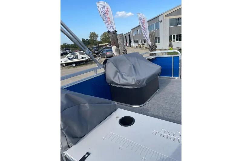 Slide: The Image of 2026 Paddle King Lo Pro Angler boat with covered seats, docked near a marina. - 9