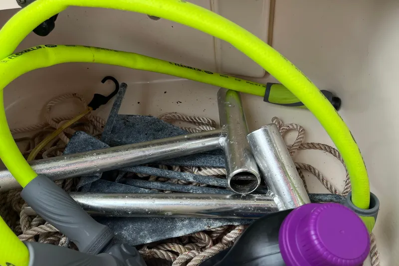 Slide: The Image of Boat storage compartment with ropes, metal pipes, and a yellow hose on a 2004 Grady-White Gulfstream 232. - 25