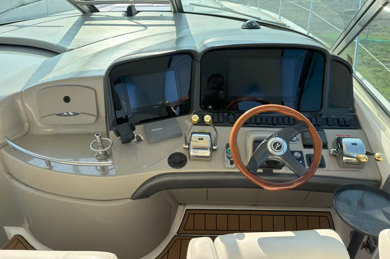 Slide: The Image of 2005 Sea Ray 420 Sundancer helm with dual screens and wooden steering wheel. - 18