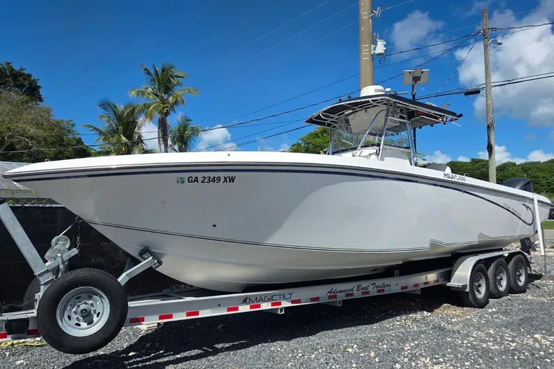 The Image of 2004 Fountain 34 CC boat on trailer, parked outdoors under clear blue sky. - 0