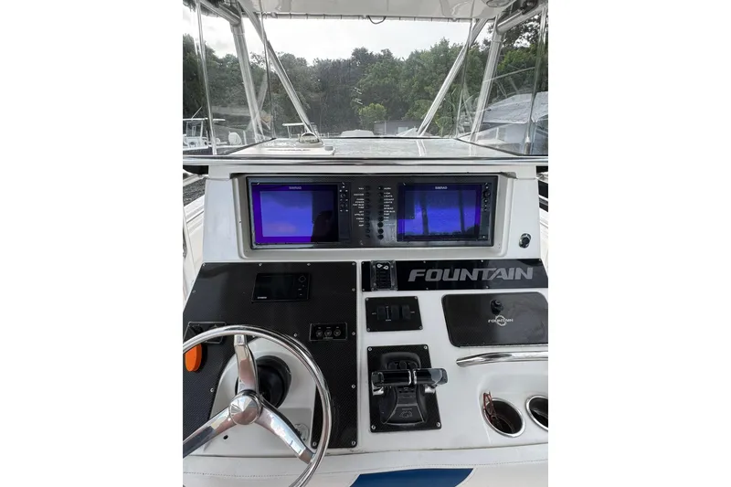 Slide: The Image of 2004 Fountain 34 CC boat dashboard with navigation screens and steering wheel. - 3
