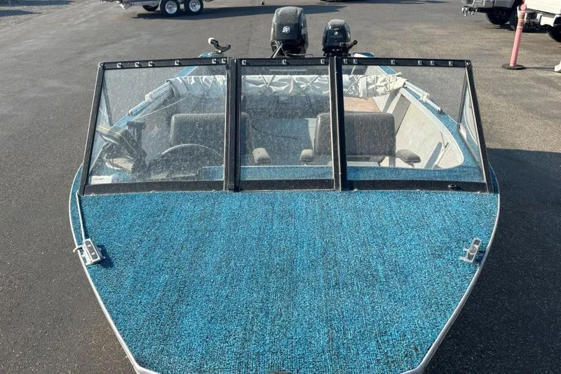 Slide: The Image of 1984 Hewescraft River Runner 16 boat with blue deck and windshield, parked on asphalt. - 3