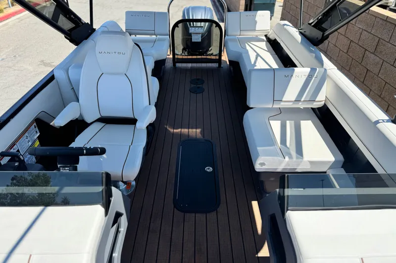 Slide: The Image of 2025 Manitou EXPLORE 26 boat interior with white seating and wood flooring. - 12