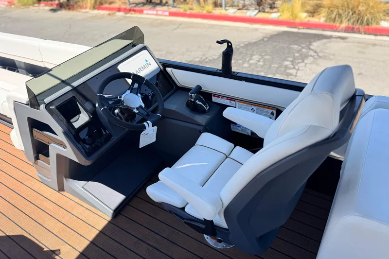 Slide: The Image of 2025 Manitou EXPLORE 26 boat cockpit with steering wheel and white captain's chair. - 23