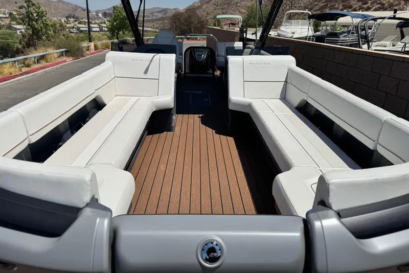 Slide: The Image of 2025 Manitou EXPLORE 26 boat interior with white seating and wooden deck. - 8