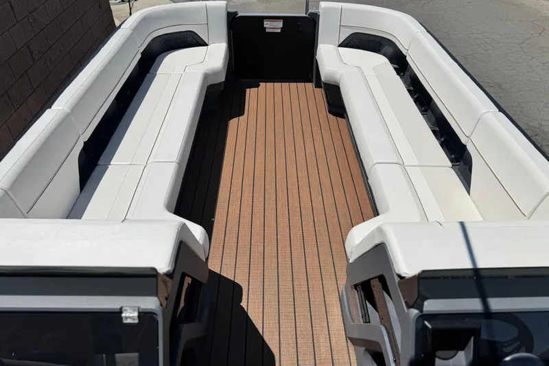 Slide: The Image of 2025 Manitou EXPLORE 26 boat interior with white seating and wooden flooring. - 9