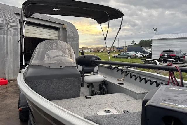 Slide: The Image of 2014 Alumacraft Escape 165 CS boat with canopy, parked outdoors near storage buildings. - 9