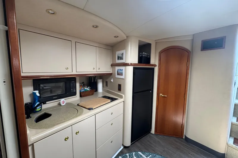 Slide: The Image of Interior of 2000 Cruisers Yachts 3870 Express, featuring a compact kitchen with cabinets and appliances. - 13