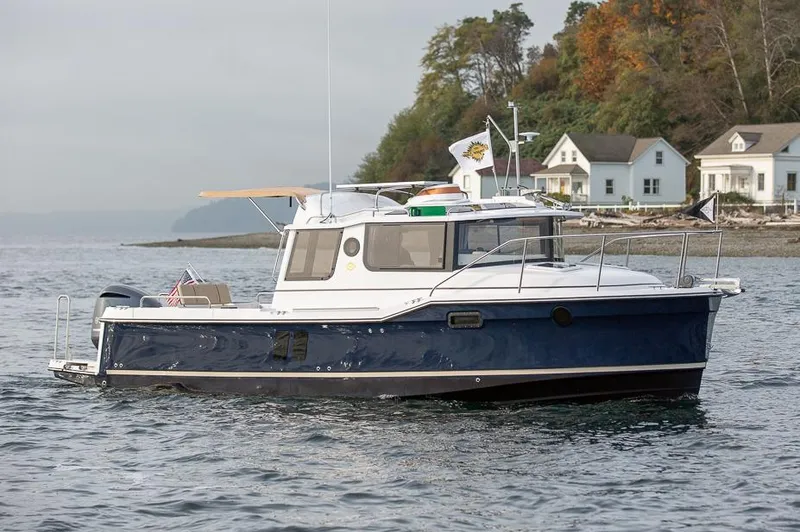 Slide: The Image of Manufacturer Provided Image: 2025 Ranger Tugs R-25 boat cruising near shoreline with houses in the background. - 1