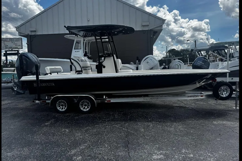 Slide: The Image of 2026 ShearWater 25 LTD boat on trailer, parked outdoors under cloudy sky. - 13