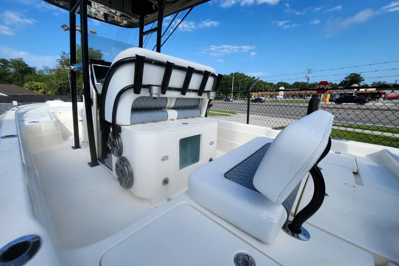 Slide: The Image of 2026 ShearWater 25 LTD boat interior with seating and speakers, parked near a fence. - 4
