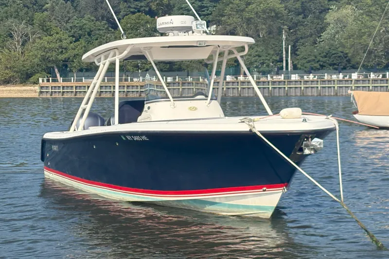 Slide: The Image of 2011 Pursuit S 280 Sport boat anchored on calm water with lush green background. - 1