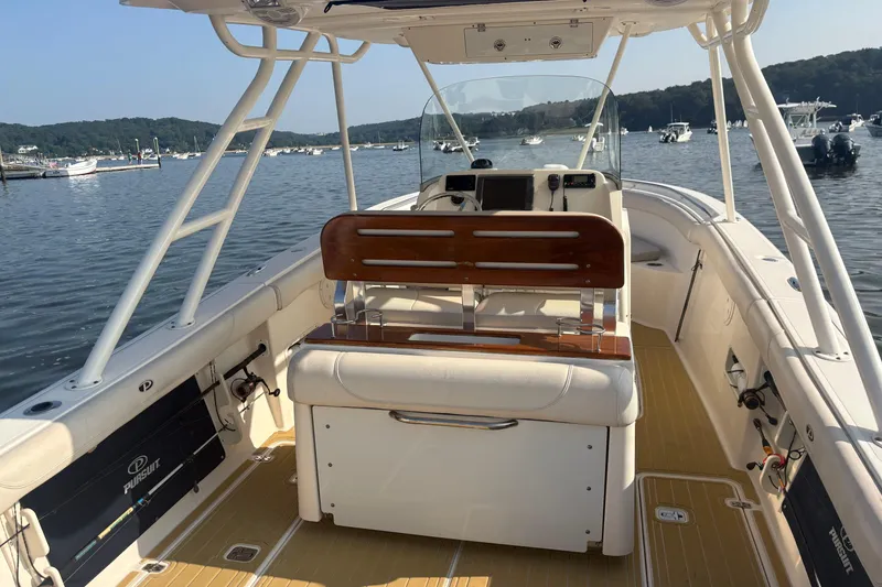 Slide: The Image of 2011 Pursuit S 280 Sport boat interior with wooden seating, docked on a calm lake. - 11