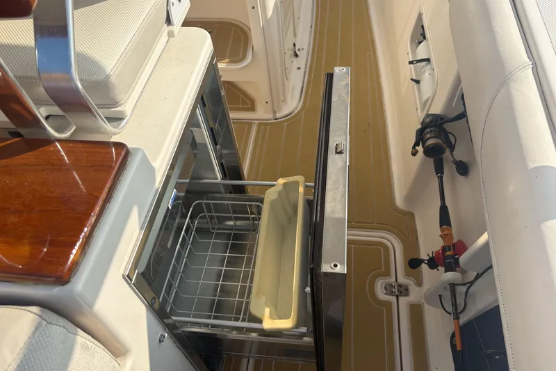 Slide: The Image of 2011 Pursuit S 280 Sport boat interior with open storage compartment and fishing rod. - 28
