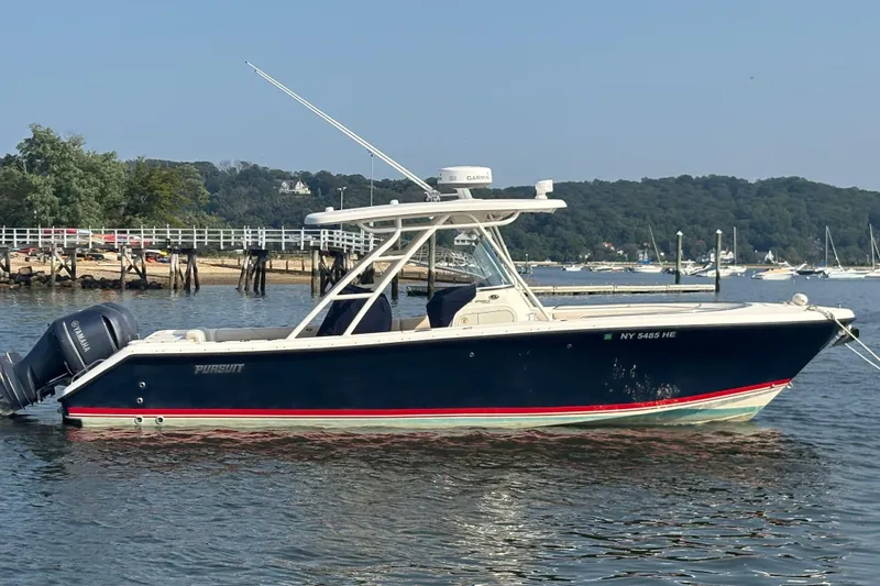 Slide: The Image of 2011 Pursuit S 280 Sport boat on calm water near a dock and trees. - 3