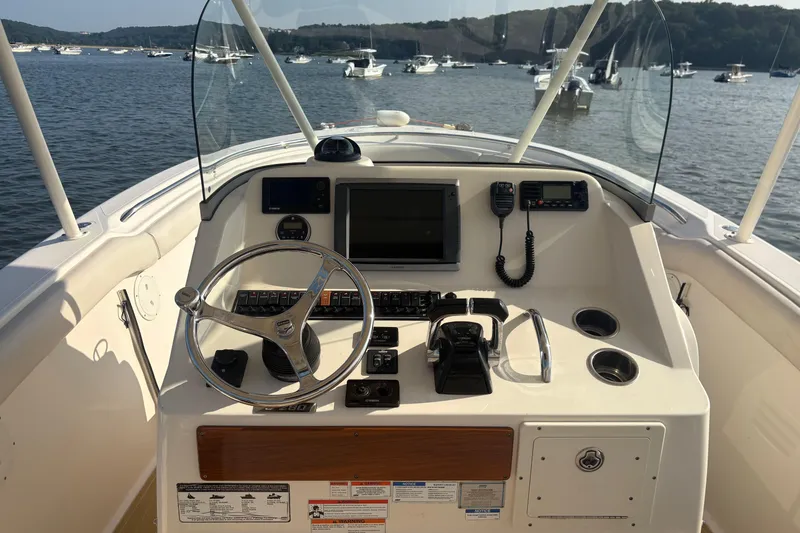 Slide: The Image of 2011 Pursuit S 280 Sport boat helm with steering wheel and control panel on calm water. - 31