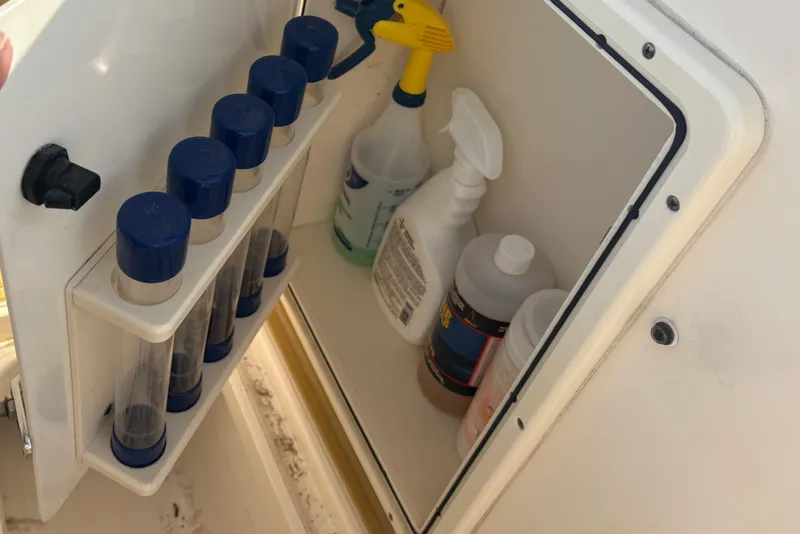 Slide: The Image of Storage compartment on a 2011 Pursuit S 280 Sport boat with cleaning supplies. - 46