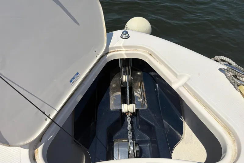 Slide: The Image of Open anchor compartment on 2011 Pursuit S 280 Sport boat, showing chain and mechanism. - 47