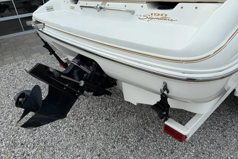 Slide: The Image of 1998 Sea Ray 190 Bow Rider boat stern with outboard motor on gravel. - 4