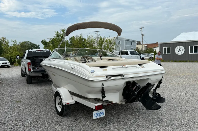 Slide: The Image of 1998 Sea Ray 190 Bow Rider boat on trailer, parked outdoors near a marina. - 5