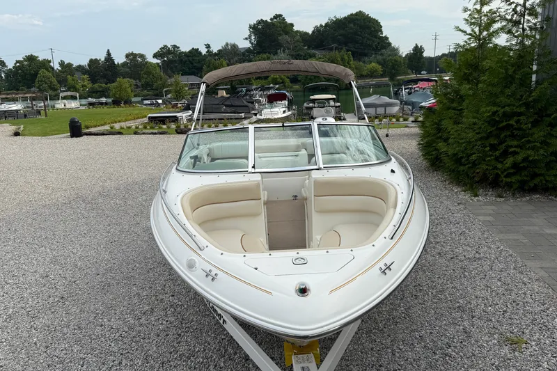 Slide: The Image of 1998 Sea Ray 190 Bow Rider boat on gravel, surrounded by greenery and other boats. - 8