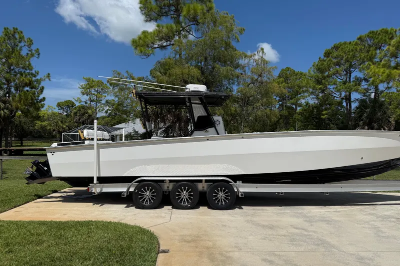 The Image of 2005 Apache 36CC boat on trailer, parked outdoors with trees in background. - 0
