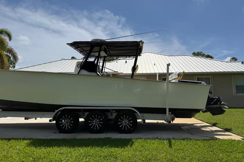 Slide: The Image of 2005 Apache 36CC boat on trailer, parked in front of a house with a metal roof. - 1