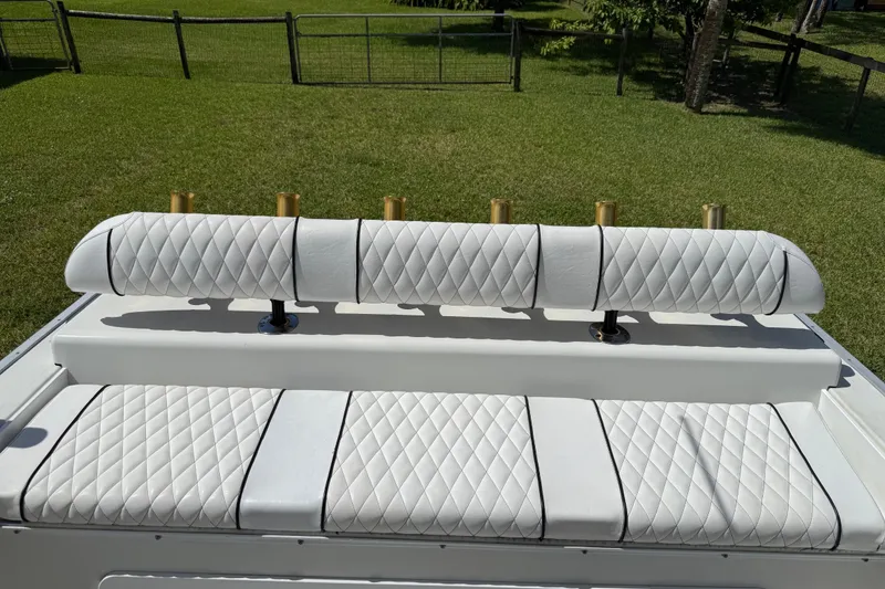Slide: The Image of White quilted seating on 2005 Apache 36CC boat, with rod holders, in a grassy area. - 12