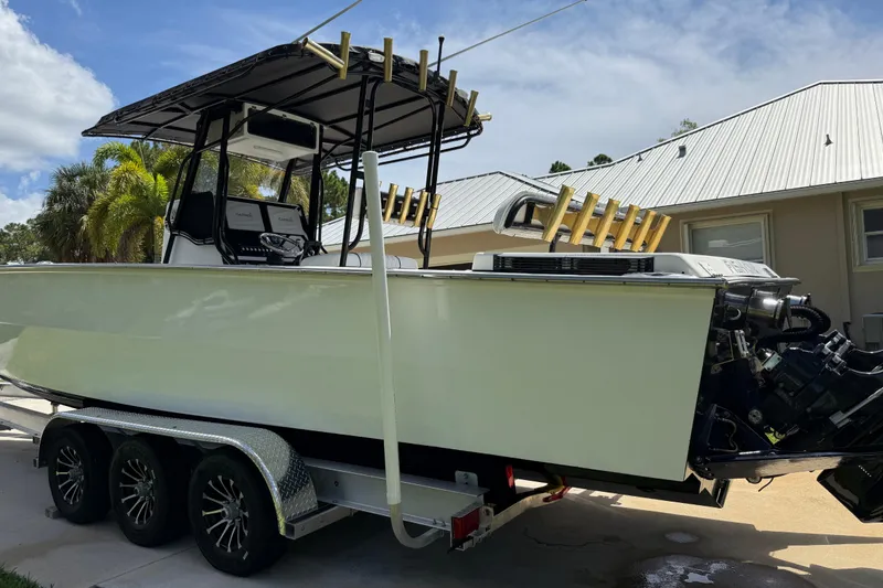 Slide: The Image of 2005 Apache 36CC boat on trailer, parked outdoors near a house with palm trees. - 2