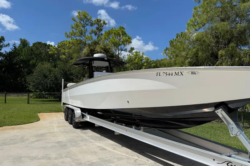 Slide: The Image of 2005 Apache 36CC boat on trailer, parked outdoors with trees in the background. - 3