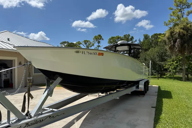 Slide: The Image of 2005 Apache 36CC boat on trailer, parked outdoors under a clear blue sky. - 6