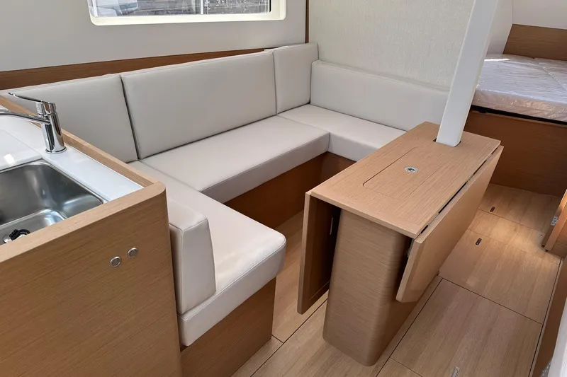 Slide: The Image of Interior of 2025 Jeanneau Sun Odyssey 380 yacht with modern seating and compact kitchen area. - 26