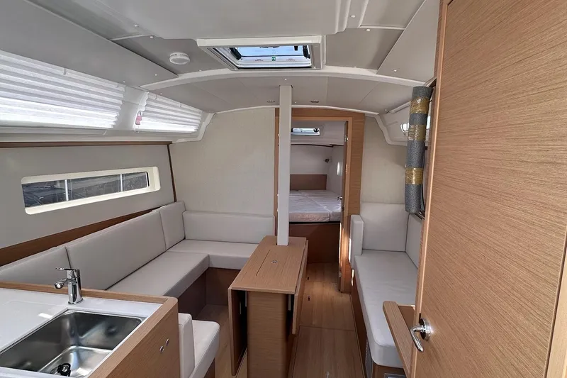 Slide: The Image of Interior of 2025 Jeanneau Sun Odyssey 380 yacht, featuring modern seating and compact kitchen area. - 28