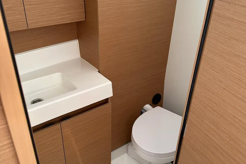 Slide: The Image of Compact bathroom in 2025 Jeanneau Sun Odyssey 380 yacht with wooden cabinetry and white fixtures. - 37