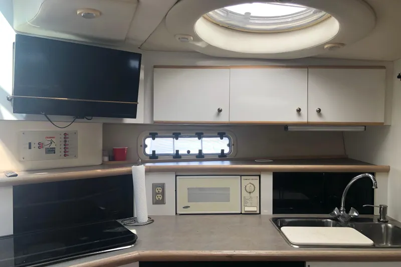 Slide: The Image of Interior of 1995 Maxum 3200 SCR boat featuring kitchen with sink, microwave, and TV. - 22