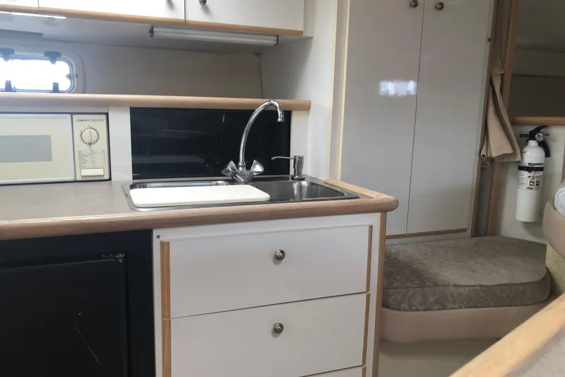Slide: The Image of 1995 Maxum 3200 SCR boat interior with kitchenette, sink, microwave, and storage cabinets. - 24