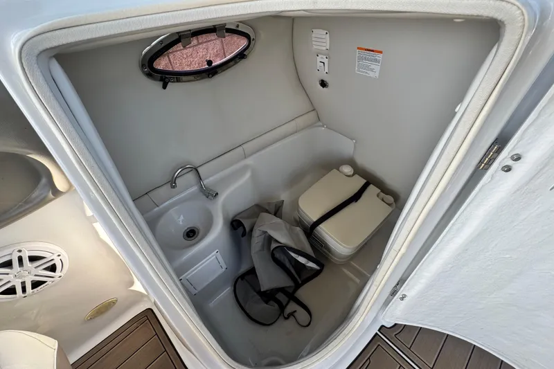 Slide: The Image of 2007 Crownline 270 BR boat interior with compact bathroom, sink, and portable toilet. - 26
