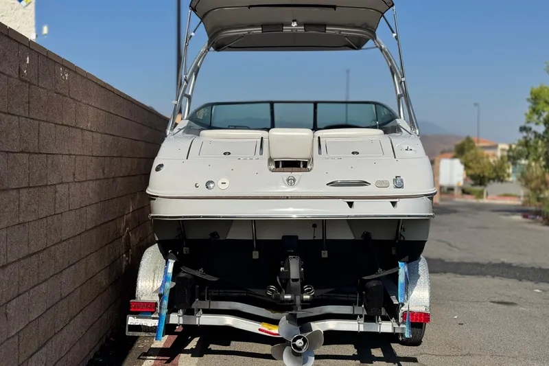 Slide: The Image of 2007 Crownline 270 BR boat on trailer, parked beside a brick wall under clear sky. - 3