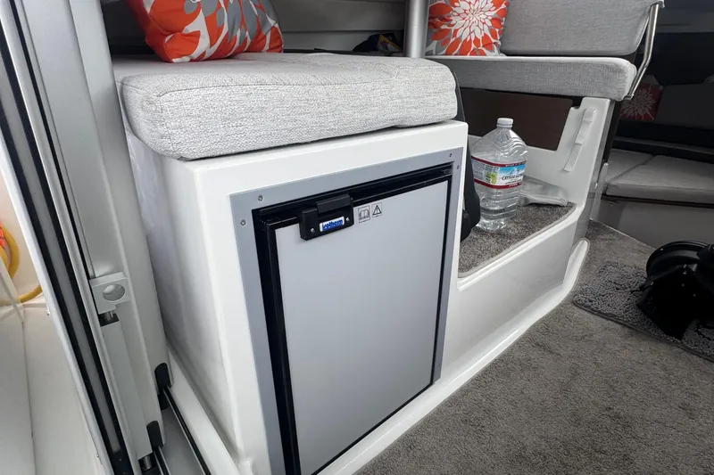 Slide: The Image of 2024 Jeanneau NC 795 interior with compact fridge and seating area. - 10