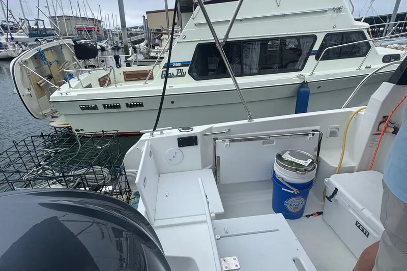 Slide: The Image of 2024 Jeanneau NC 795 boat docked at marina with fishing gear and cooler. - 8