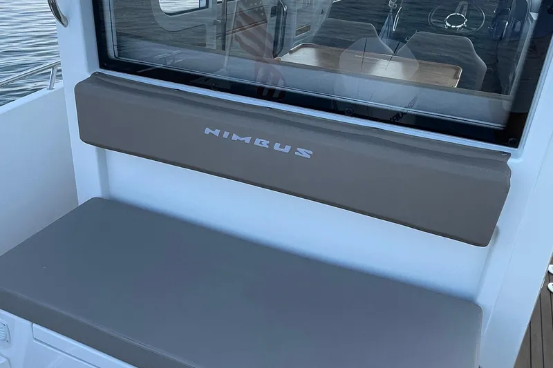 Slide: The Image of 2023 Nimbus c9-30 boat interior with cushioned seating and window view. - 15