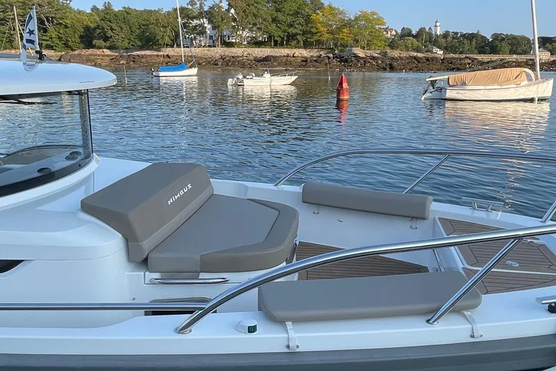 Slide: The Image of 2023 Nimbus C9-30 boat with cushioned seating, docked in a serene harbor. - 19