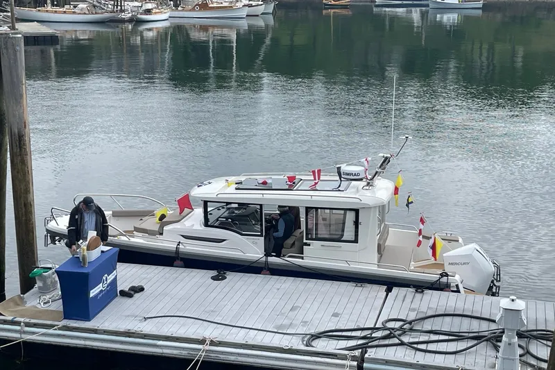 Slide: The Image of 2023 Nimbus c9-30 boat docked, decorated with flags, in a calm marina setting. - 8