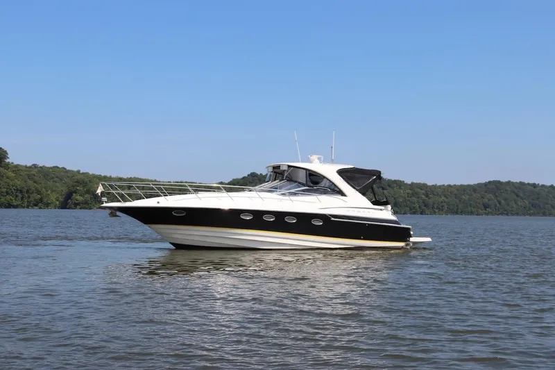 The Image of 2006 Regal Commodore 4460 yacht cruising on a serene lake with forested shoreline. - 0