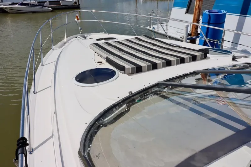 Slide: The Image of 2006 Regal Commodore 4460 yacht with striped sun pad on deck, docked in marina. - 19