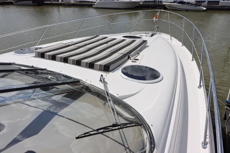 Slide: The Image of 2006 Regal Commodore 4460 yacht with striped sun pad, docked in marina. - 20