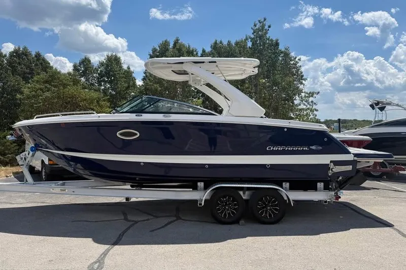 Slide: The Image of 2022 Chaparral 28 Surf boat on trailer, parked outdoors under a cloudy sky. - 0