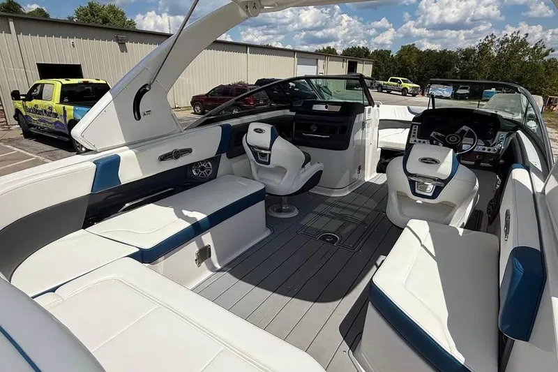 Slide: The Image of 2022 Chaparral 28 Surf boat interior with white and blue seating, parked outdoors. - 11