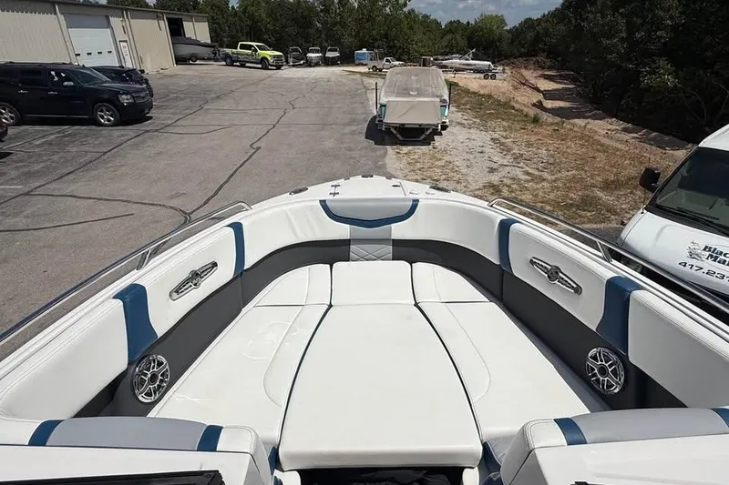 Slide: The Image of 2022 Chaparral 28 Surf boat interior with white and blue seating, parked outdoors. - 15